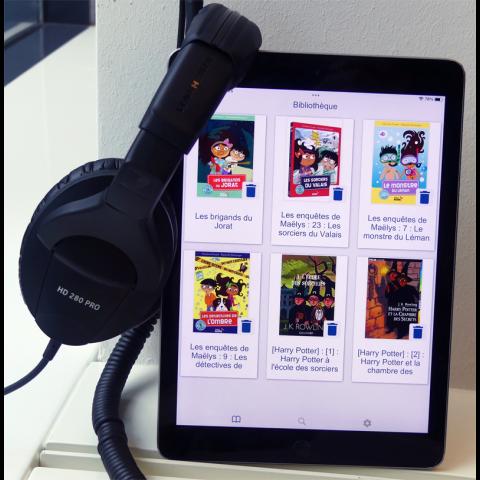 Tablette avec l'application biblioplayer iOS ouverte, casque d'écoute branché